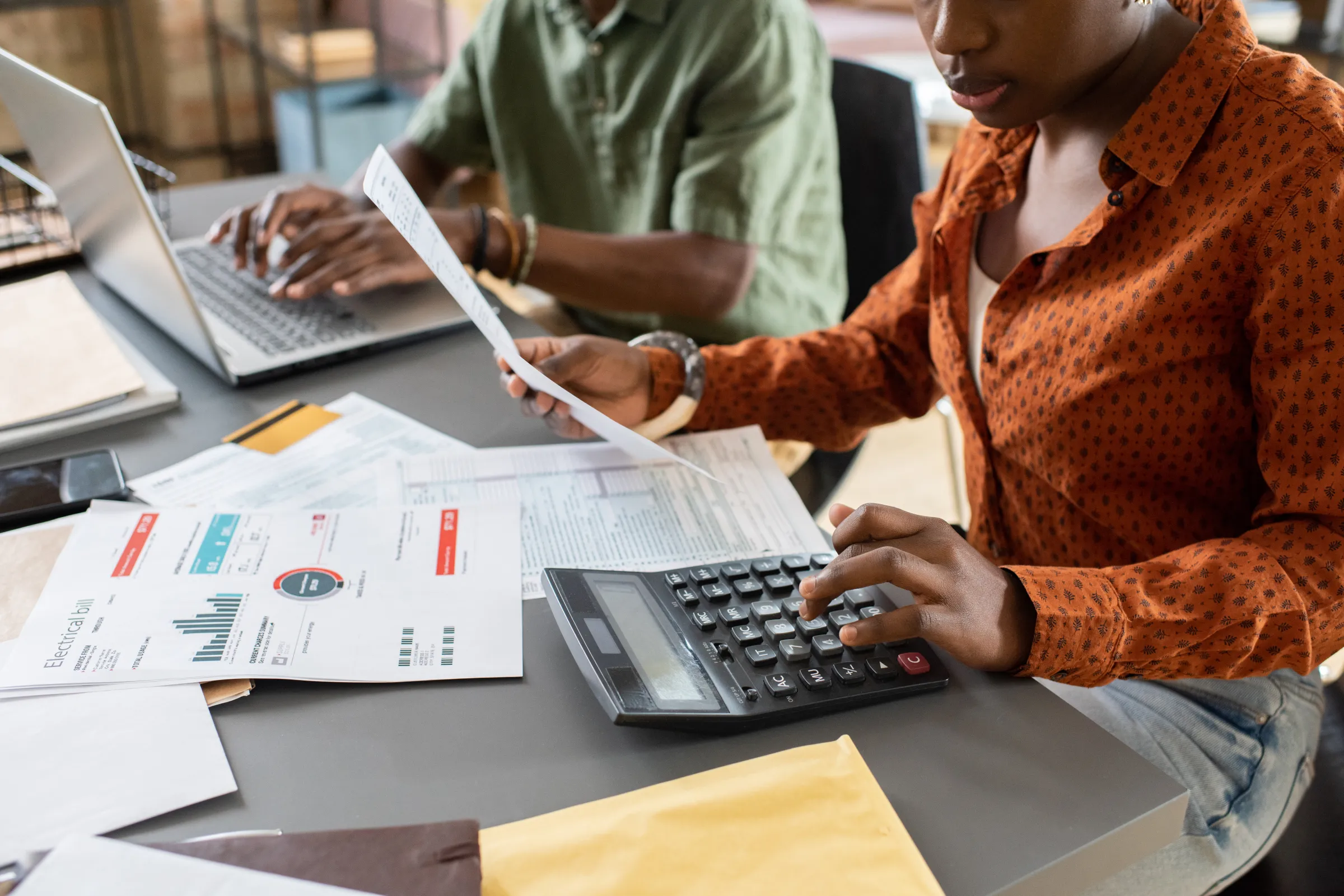 Two Wakairu Consultants accountants reviewing financial statements with a calculator and laptop at the Milimani, Nairobi office
